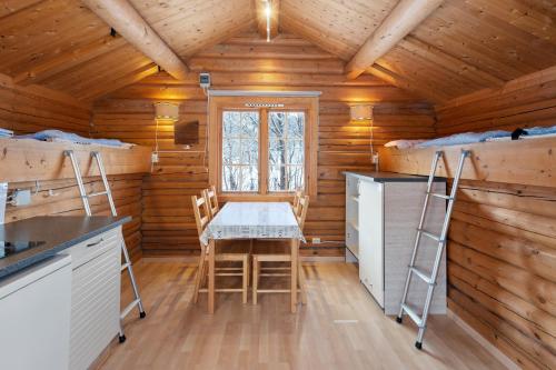 Una cocina con mesa y sillas en una cabaña de madera. en Birkelund camping, en Geilo