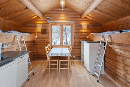eine Küche mit einem Tisch und Stühlen in einem Blockhaus in der Unterkunft Birkelund camping in Hovet