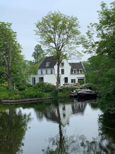 a white house sitting next to a river at 'Room Eleven' aan de Vecht in Vreeland