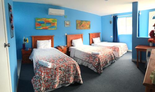1 dormitorio con 2 camas y pared azul en Mansion Giahn Bed & Breakfast, en Cancún
