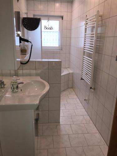 een witte badkamer met een wastafel en een douche bij Dat Sottje Huus in Wilhelmshaven