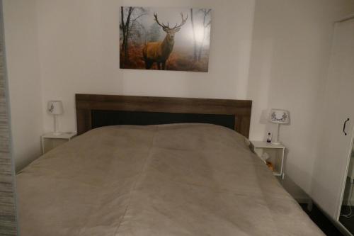a bedroom with a bed with a picture of a deer on the wall at Kleine Harzflucht in Altenau