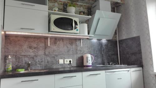 a kitchen with white cabinets and a microwave at SauleS in Ventspils