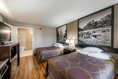 a hotel room with two beds and a flat screen tv at Super 8 by Wyndham Alexander City in Alexander City