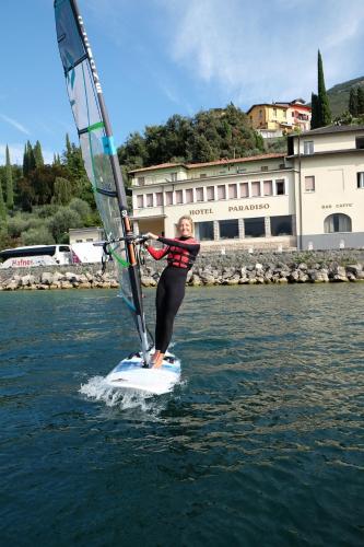 a woman standing on a wind sail on the water at Hotel Paradiso Conca d'Oro in Nago-Torbole
