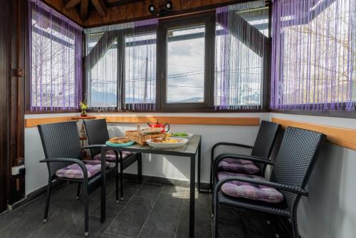 uma sala de jantar com mesa, cadeiras e janelas em Apartment Rašće em Ogulin