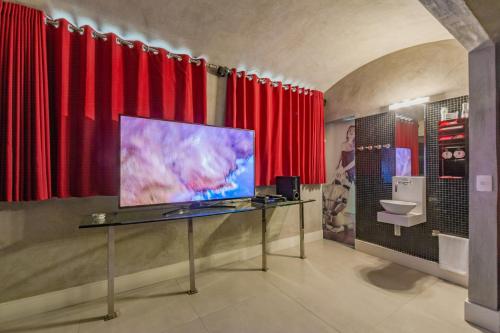 a room with red curtains and a flat screen tv at Spa urbano Motel Adult Only in Fortaleza