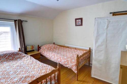 a bedroom with two beds and a window at Taffs Well Cottage in Taffs Well