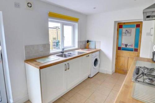 a kitchen with a sink and a washing machine at Taffs Well Cottage in Taffs Well