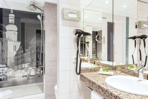 baño con 2 lavabos y teléfono en la pared en NH Dortmund, en Dortmund