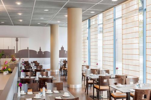 un restaurante con mesas, sillas y ventanas en NH Dortmund, en Dortmund