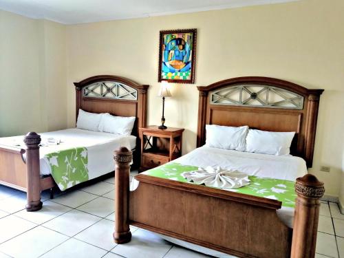 a bedroom with two beds and a painting on the wall at Hotel Carnaval in La Ceiba