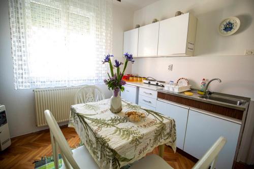 una cucina con un tavolo con un vaso di fiori sopra di Apartmani Didić a Soko Banja