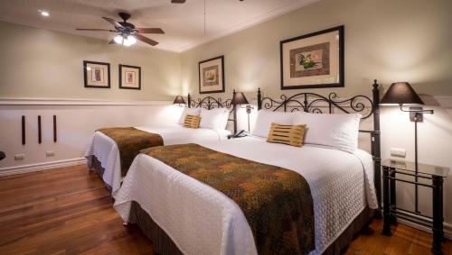 a bedroom with two beds and a ceiling fan at Grano de Oro Hotel in San José