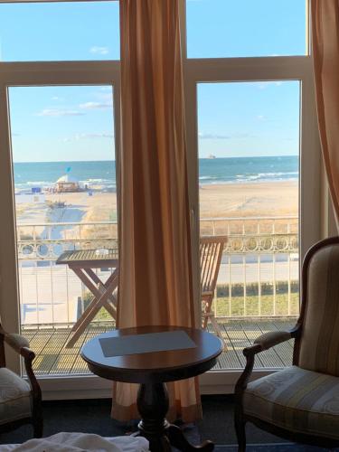 a room with two chairs and a table and a view of the ocean at Hotel Bellevue Warnemünde in Warnemünde