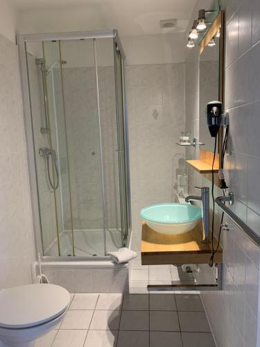 a bathroom with a shower, toilet, sink and tub at Hotel Bellevue Warnemünde in Warnemünde