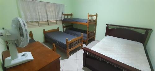 a small room with two beds and a fan at Chácara em Araçoiaba da Serra in Araçoiaba da Serra