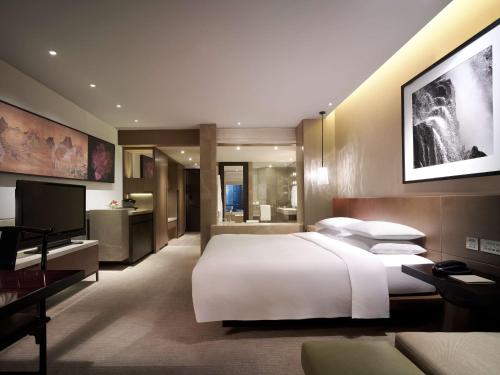 a bedroom with a large white bed and a television at Grand Hyatt Hong Kong in Hong Kong