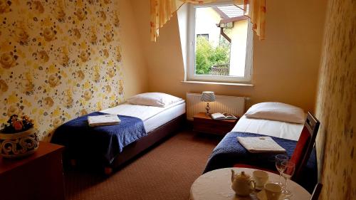two beds in a room with a table and a window at Villa Bri in Łeba