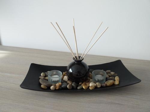a black vase sitting on a black plate with rocks at Seaside Home Apartment in Mangalia