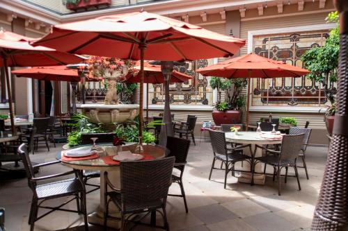 a patio with tables and chairs with red umbrellas at Grano de Oro Hotel in San José