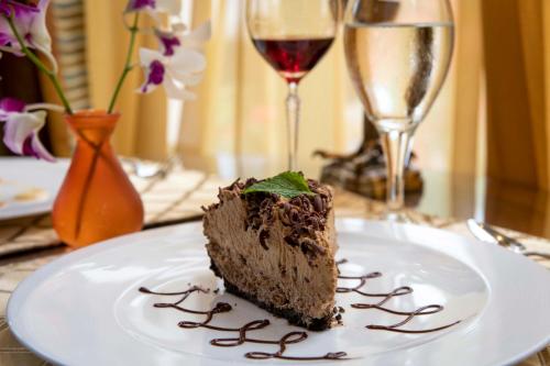 a piece of chocolate cake on a plate with wine glasses at Grano de Oro Hotel in San José