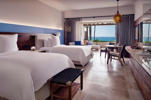 Habitación de hotel con 2 camas y sala de estar. en Four Seasons Resort Punta Mita en Punta Mita