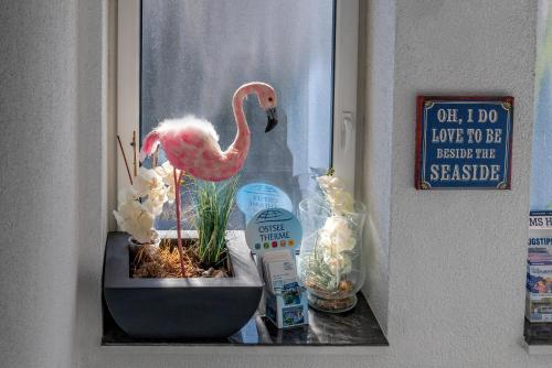 a fake pink flamingo in a planter in a window at Seaside-Strandhotel in Timmendorfer Strand