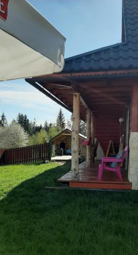 a porch with a pink chair and a house at Babiogórskie Domki in Lipnica Wielka