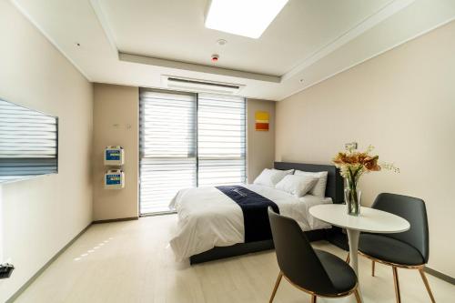 a bedroom with a bed and a table and chairs at Hi Ocean Gyeongpo in Gangneung