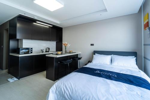 a bedroom with a bed and a kitchen in it at Hi Ocean Gyeongpo in Gangneung