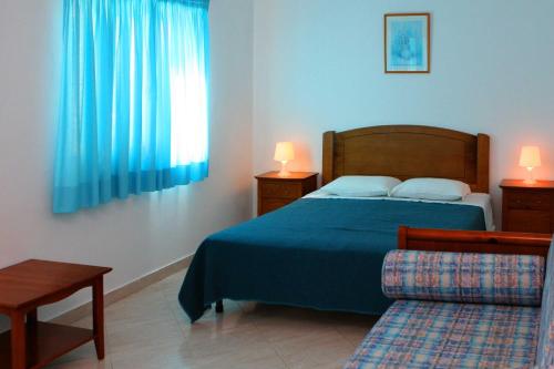 a bedroom with a bed and a window with blue curtains at Villas King's in Albufeira