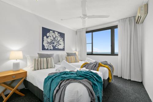 two beds in a room with a window at Cairns Aquarius in Cairns
