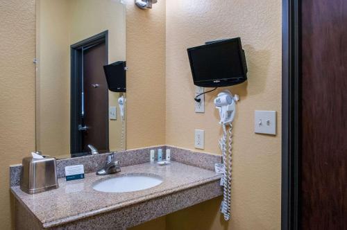 uma casa de banho com lavatório, telefone e televisão em Quality Inn & Suites Slidell em Slidell