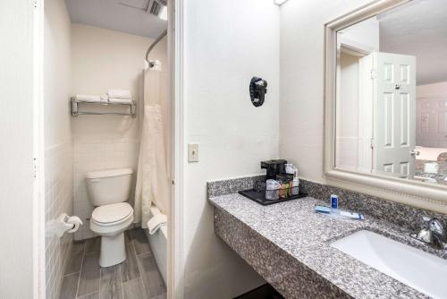 a bathroom with a sink and a toilet and a mirror at Rodeway Inn in Cadiz