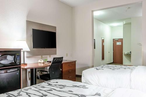 a hotel room with two beds and a desk and a tv at Sleep Inn & Suites in Hobbs