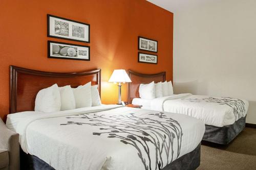 two beds in a hotel room with orange walls at Sleep Inn & Suites in Hobbs