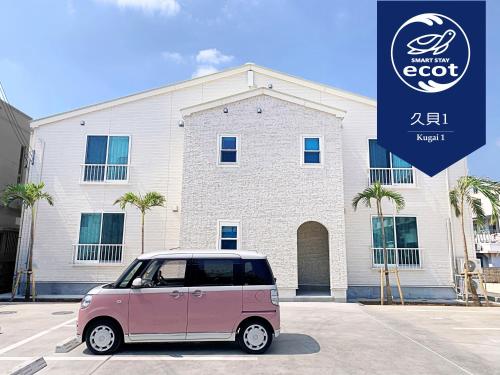宮古島的住宿－Ecot Kugai 1，停在大楼前的粉红色小汽车