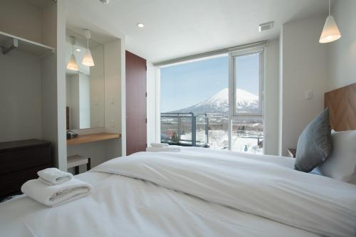 a bedroom with a large white bed with a mountain view at Niseko Landmark View in Kutchan