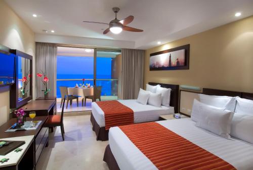 巴亞爾塔港的住宿－Sunset Plaza Beach Resort Puerto Vallarta All Inclusive，一间酒店客房,设有两张床和一间餐厅