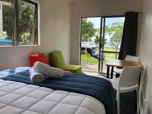 a bedroom with a bed and two chairs and a table at Takapuna Beach Holiday Park in Auckland