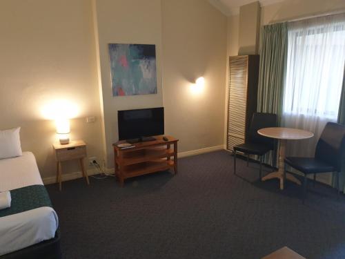 a hotel room with a bed and a flat screen tv at Greenways Apartments in Adelaide