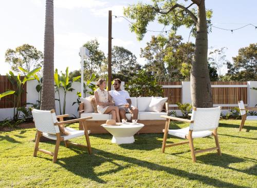 two people sitting on a couch in a yard at Loea Boutique Hotel in Maroochydore