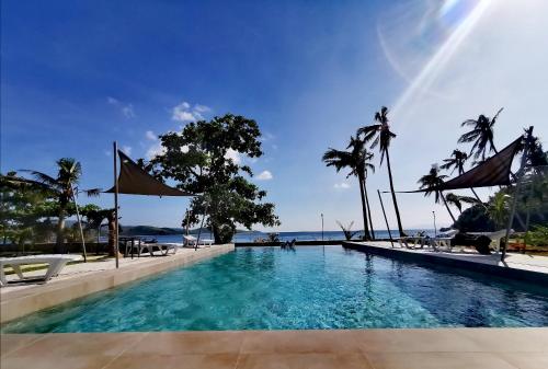 a swimming pool with palm trees and the ocean at Sunset Cove Beach & Dive Resort in Romblon