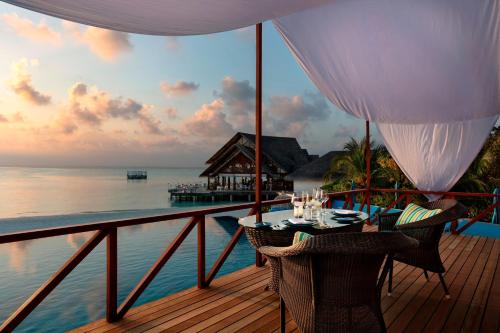 a balcony with a table and chairs on the ocean at Anantara Dhigu Maldives Resort - Special Offer On Transfer Rates For Summer 2024 in South Male Atoll