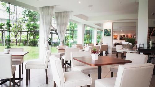 a restaurant with white chairs and tables and windows at The White Garden Premier Saraburi in Ban Dao Ruang