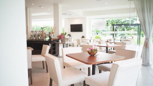 a dining room with tables and white chairs at The White Garden Premier Saraburi in Ban Dao Ruang