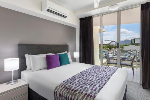 a bedroom with a bed and a balcony with a view at Park Regis City Quays in Cairns