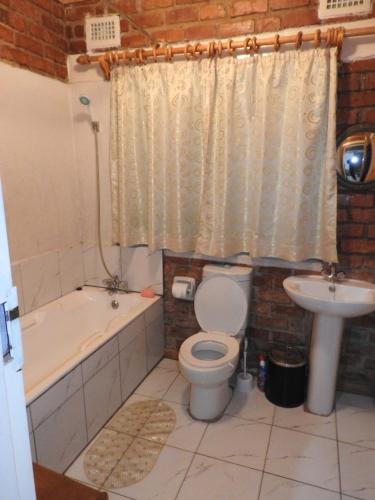 La salle de bains est pourvue de toilettes, d'une baignoire et d'un lavabo. dans l'établissement Madrugada, à Umtali