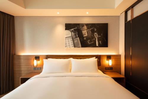 a bedroom with a large white bed with two lights at Mercure Ambassador Seoul Hongdae in Seoul